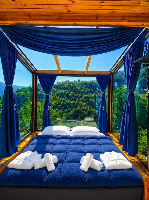 a bedroom with a blue bed with a large window at Hill House Merisi in Merisi