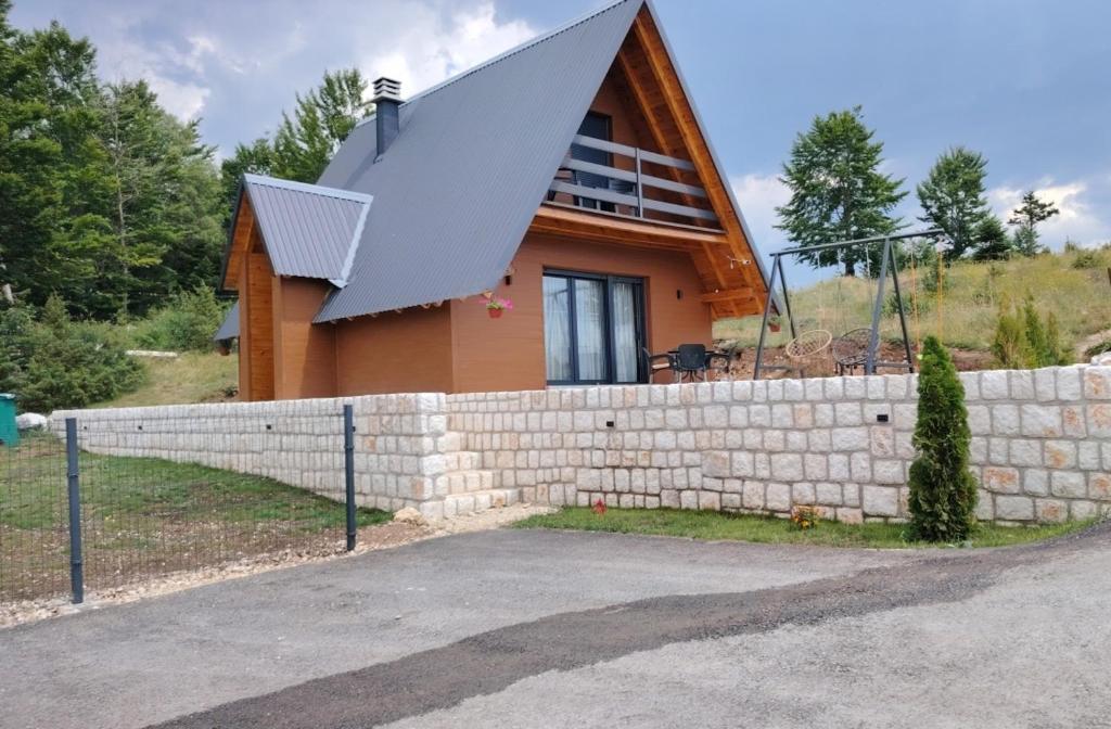 a house with a pointed roof on top of a wall at Durmitor sky in Žabljak