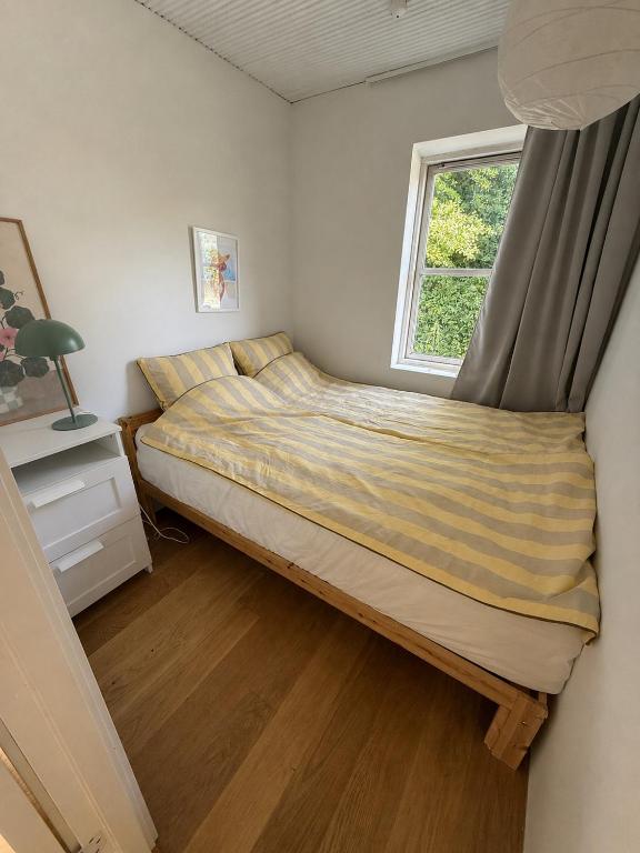 a bed in a small bedroom with a window at Krageholmshytten in Karrebæksminde