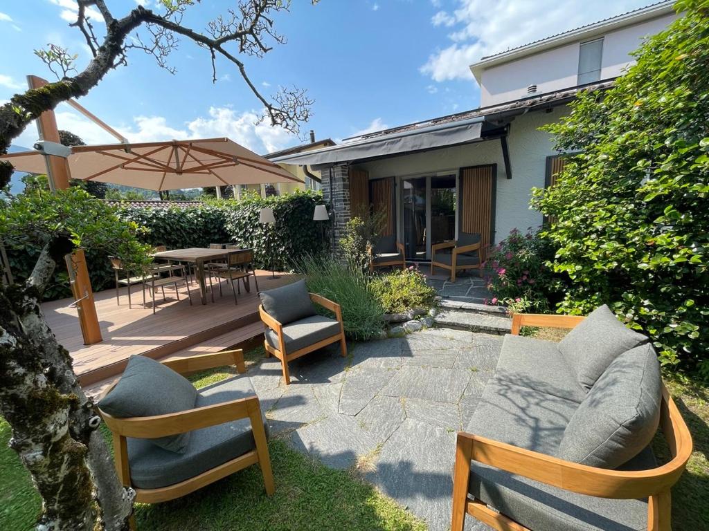 a patio with chairs and a table and an umbrella at Ascona Casa Mamina A in Ascona