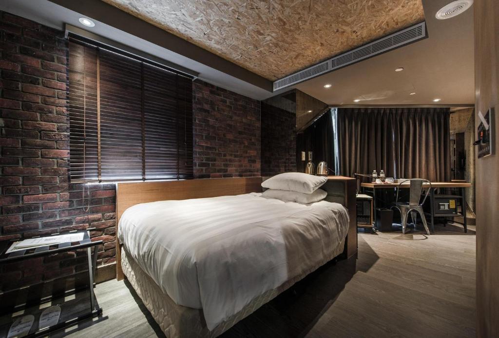 um quarto com uma cama e uma parede de tijolos em City Suites - Kaohsiung Pier2 em Kaohsiung
