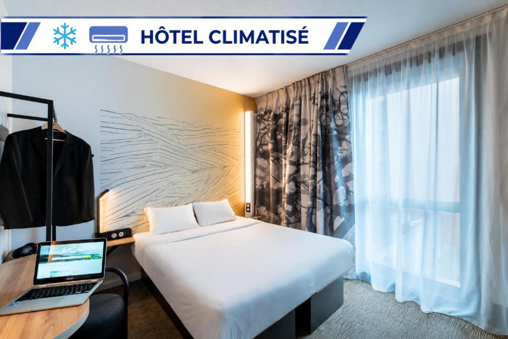 a hotel room with a bed and a laptop on a desk at B&B HOTEL Saintes in Saintes