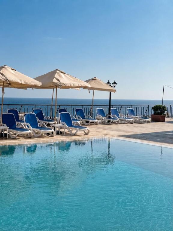 a group of chairs and umbrellas next to a swimming pool at Vivaldi Hotel in St. Julianʼs