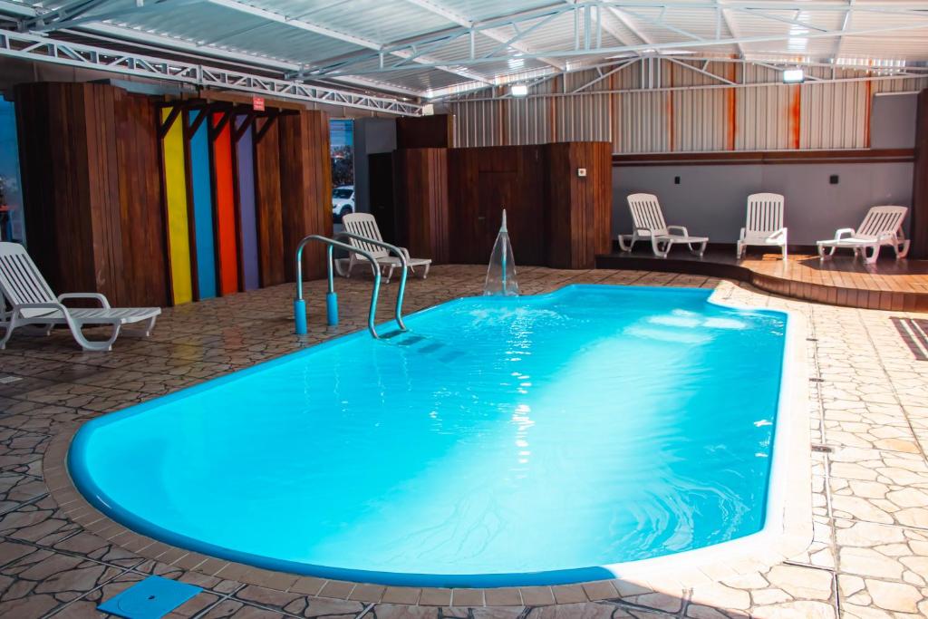 a large pool in a room with chairs at Hotel Conexão in Penha