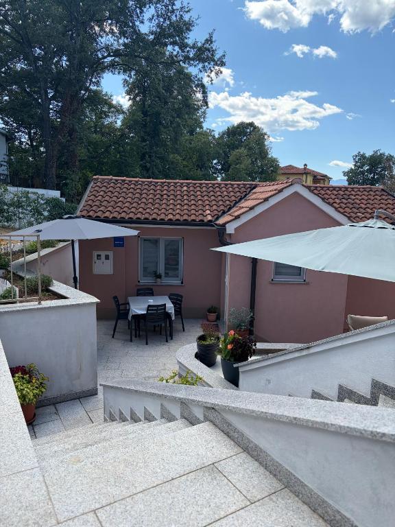 a house with a patio with a table and an umbrella at Apartman Indy in Marčelji