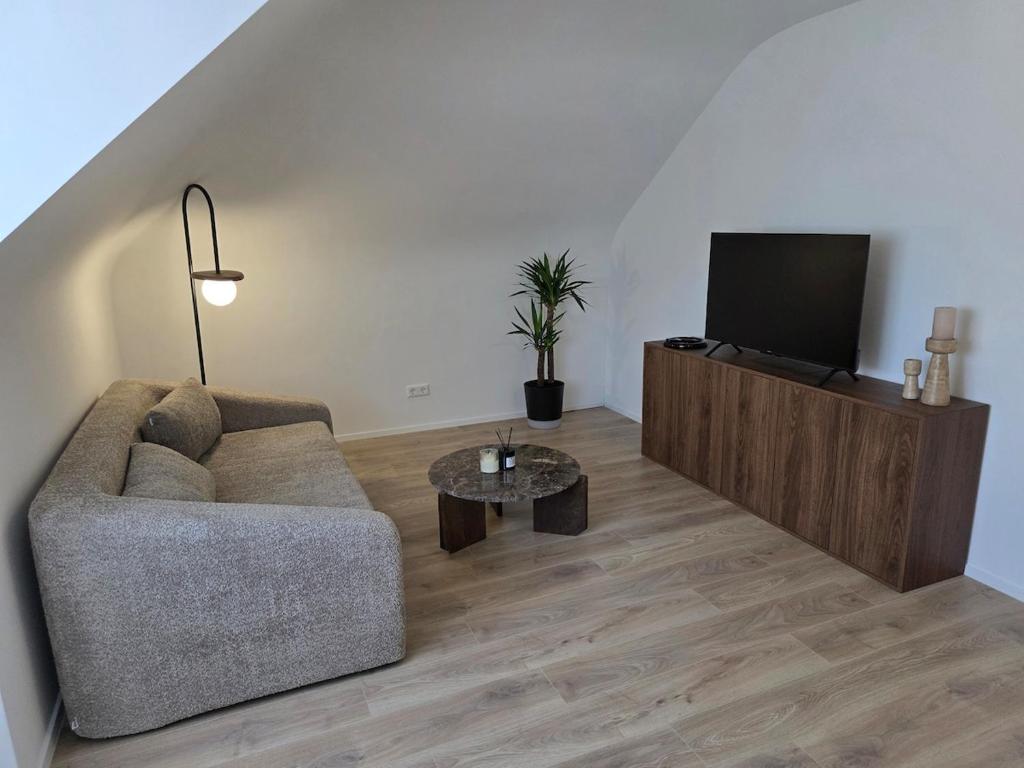 a living room with a couch and a flat screen tv at Design-Dachgeschosswohnung am Schwarzwald in Pforzheim