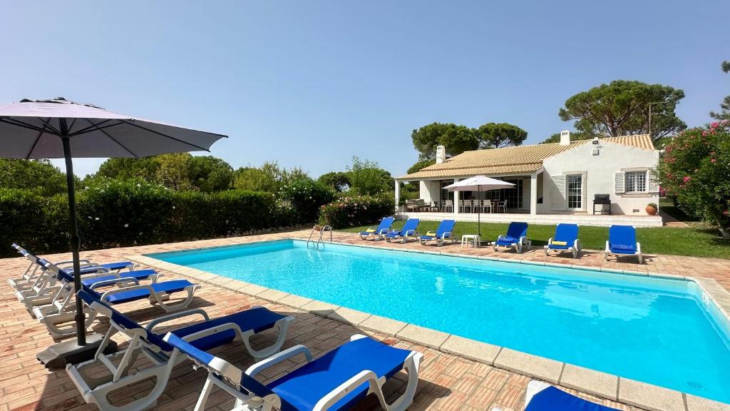 a swimming pool with chairs and an umbrella at Sol - Private Pool - 14 Guests - Vilamoura in Vilamoura