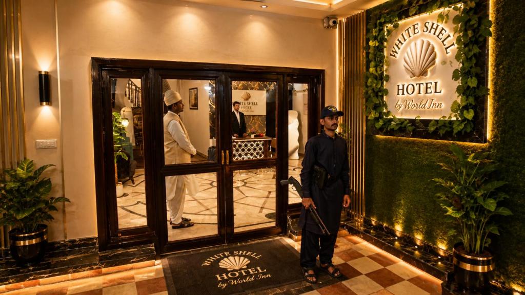 a man is standing in front of a hotel at White Shell Hotel in Karachi