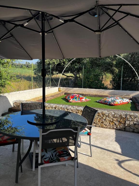 a table and chairs with an umbrella on a patio at Maisonnette et Campagne Provençale, avec Piscine in Orgon