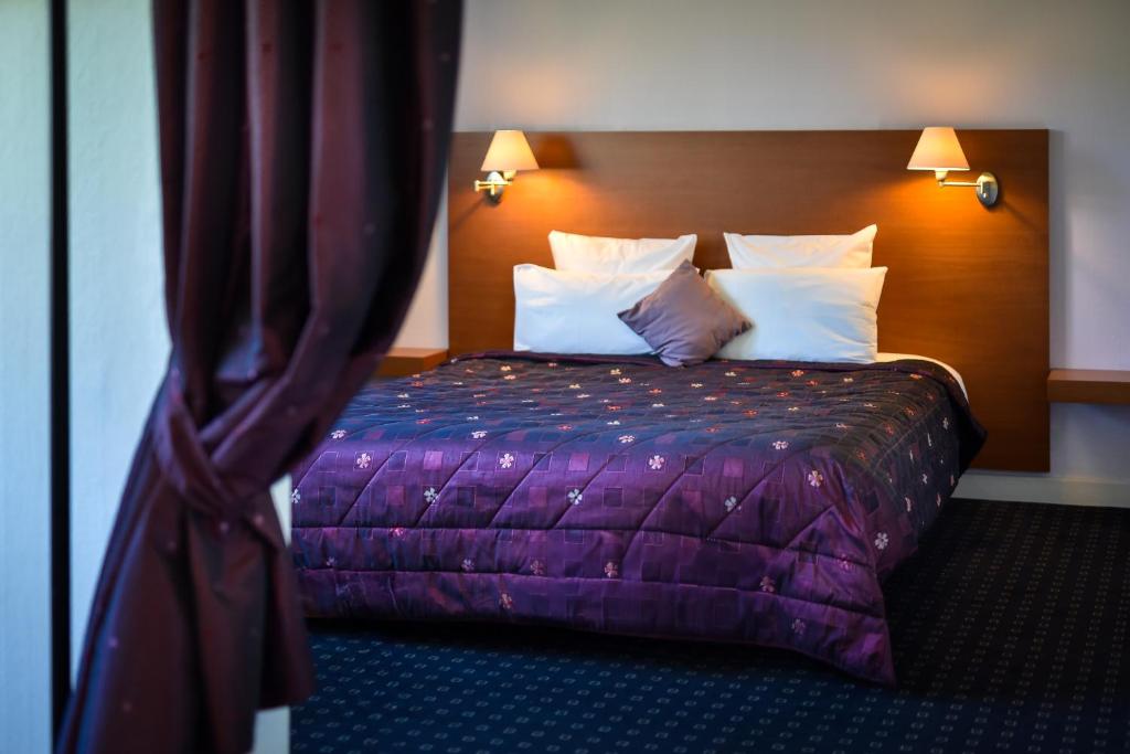 a hotel room with a bed with purple sheets and pillows at Logis Hôtel Restaurant La Palette in Wettolsheim