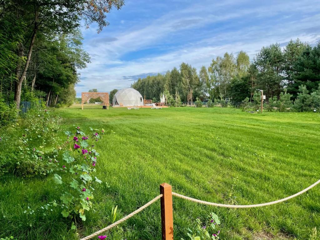 a fence in a field with a dome in the background at beGLAMP - Glamping nad Zalewem Próba in Brzeźnio