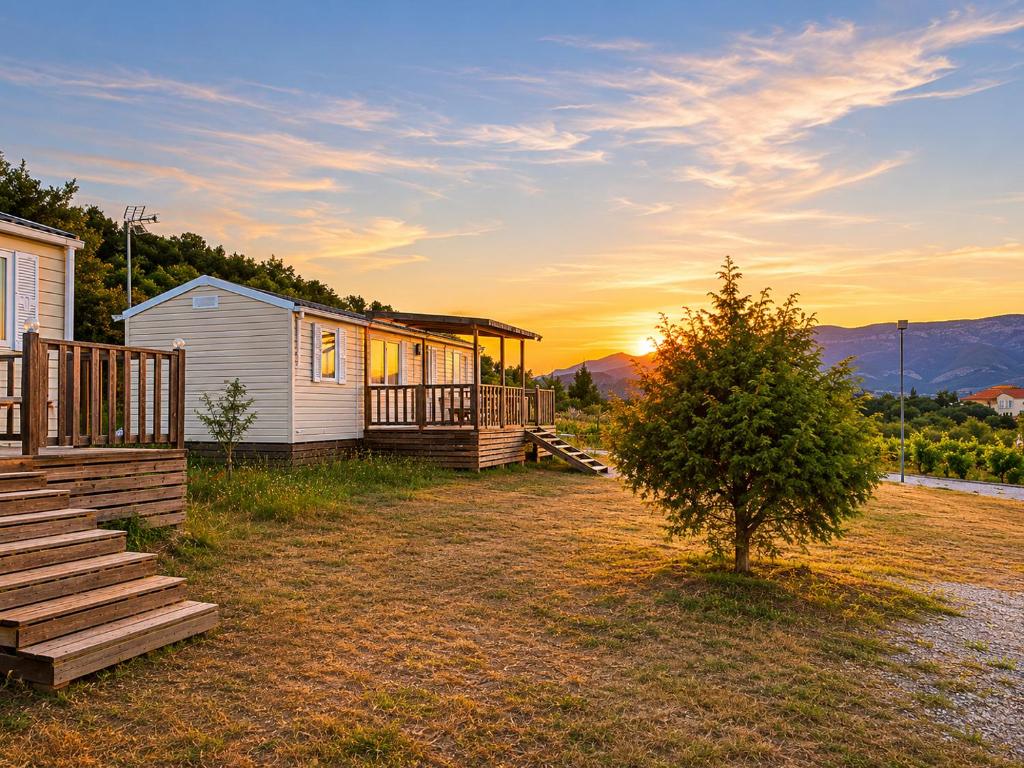 a house with a porch and a tree in front of it at Camping Nysa Paziols in Paziols