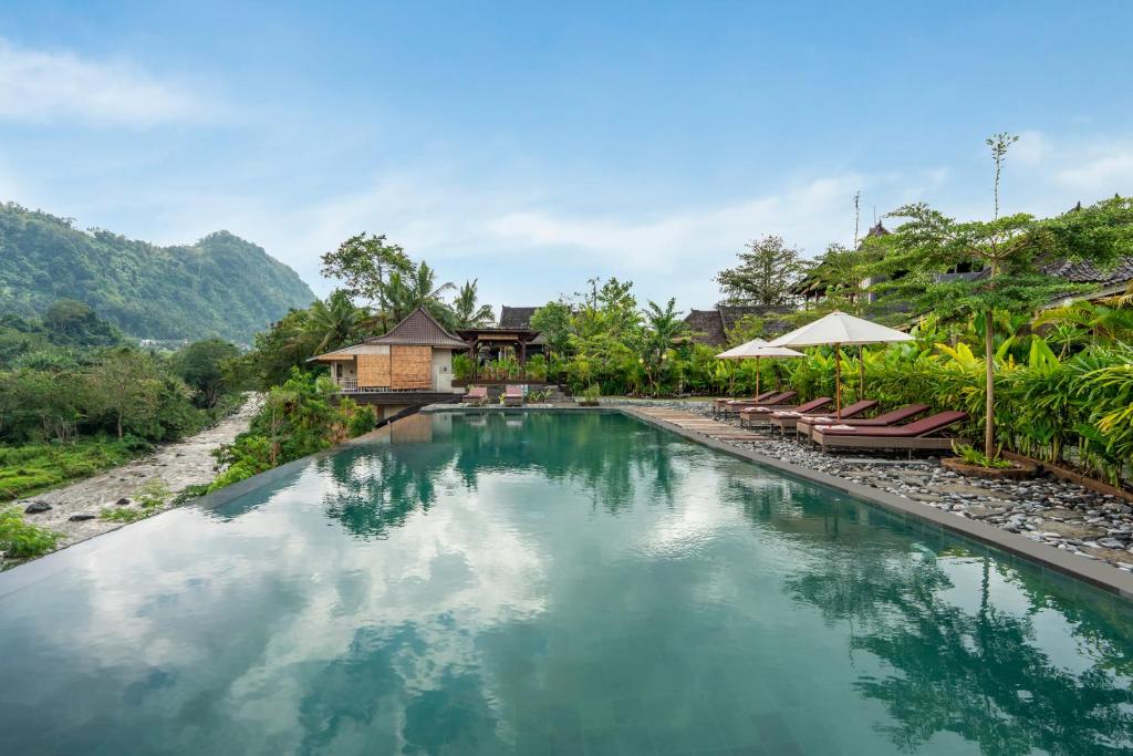 a pool at a resort with chairs and umbrellas at ArtVilla Sidemen River in Sidemen