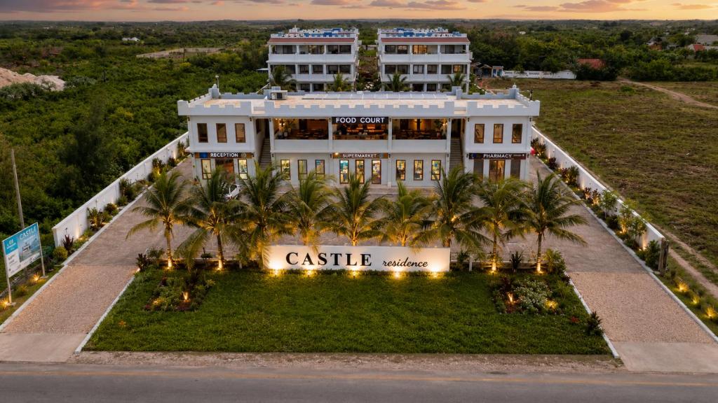 a large white building with palm trees in front of it at Castle Residence by Aura Space in Paje