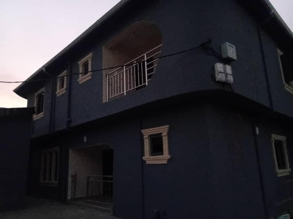 a blue building with two windows and a balcony at ifetomitola in Iseri-Osun