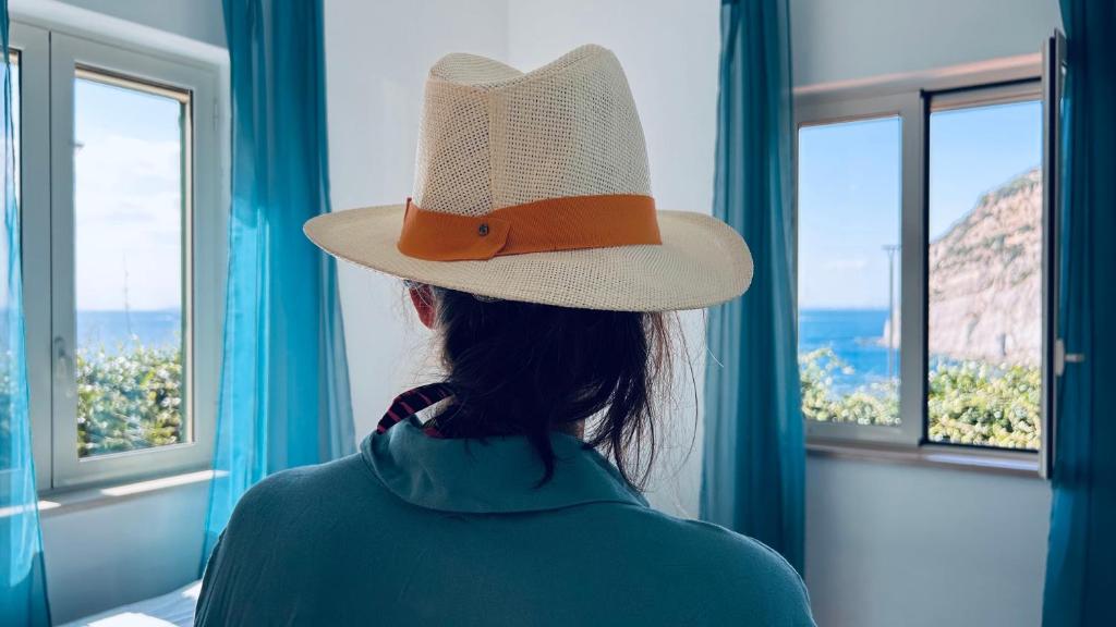 メータにあるL'Ebbrezza di mareの帽子をかぶった女性が窓の外を見ている