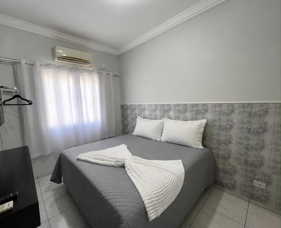 a bedroom with a bed with two pillows on it at Flat Centro 301 in Tangara da Serra