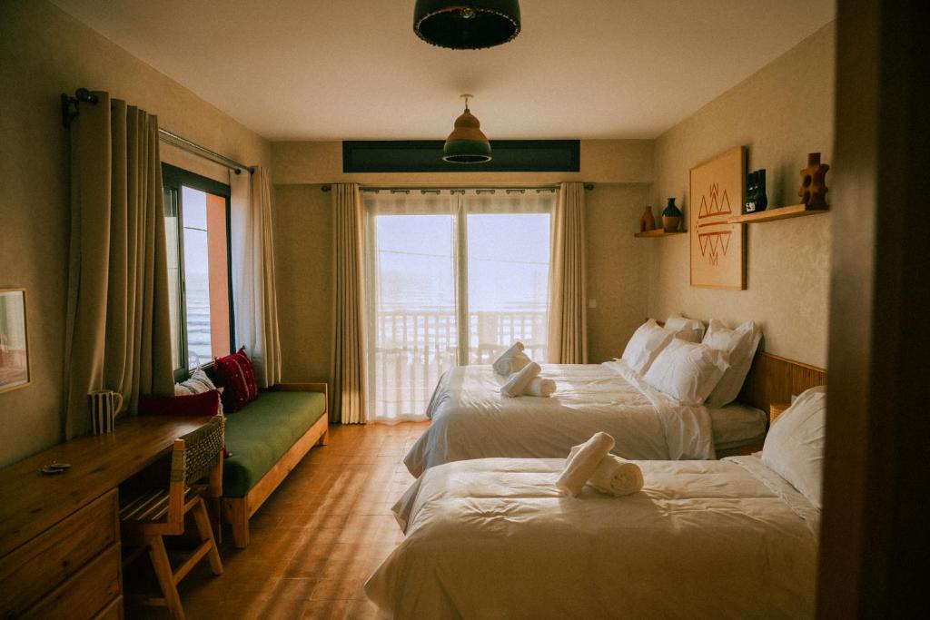 a hotel room with two beds and a window at Flooka Surf Yoga in Imsouane