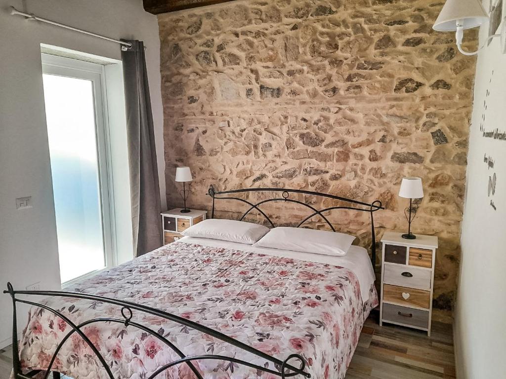 a bedroom with a bed and a stone wall at Appartamenti Monte Selce in Monselice