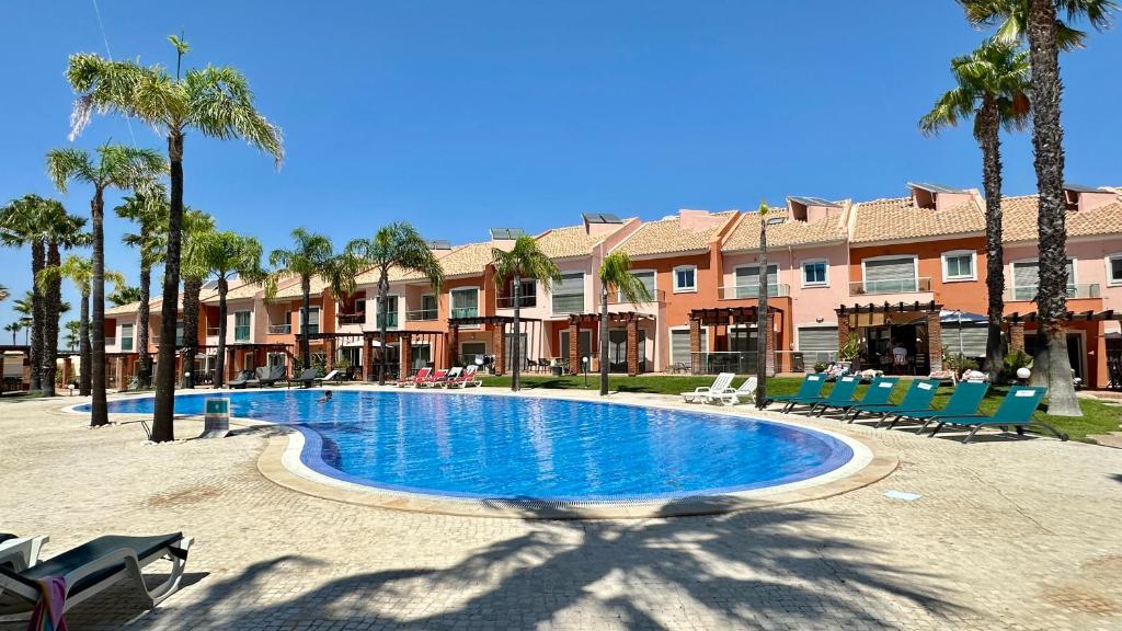 a swimming pool in a resort with chairs and palm trees at Santa Maria N - Shared Pool - 8 Guests - Albufeira in Albufeira