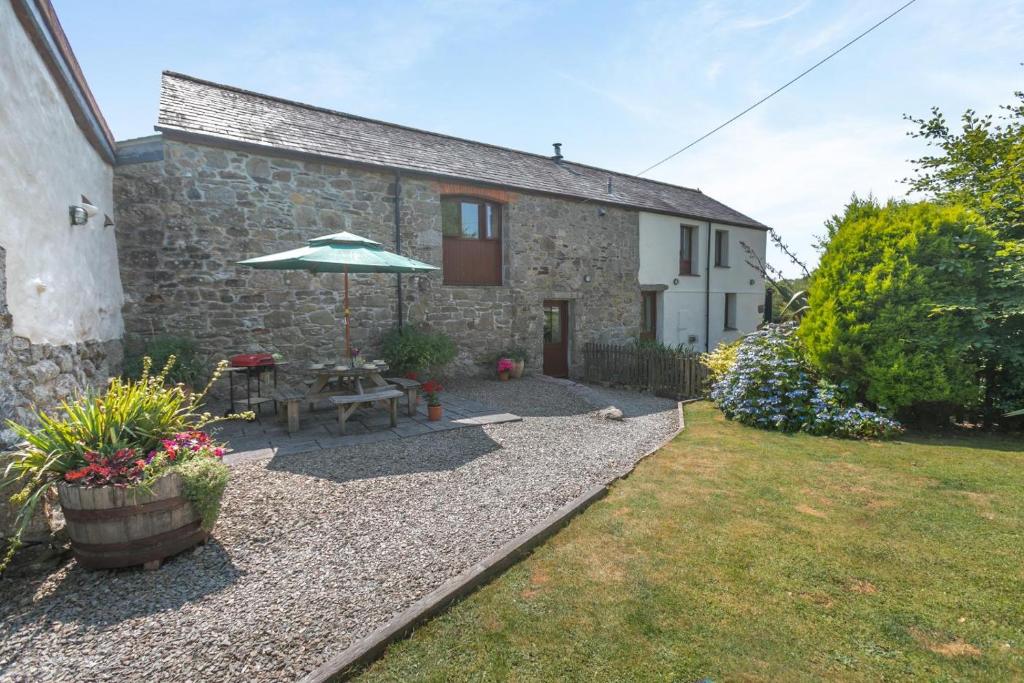 a stone cottage with an umbrella and a garden at 3 Bed in Bodmin oc-ltbra in Cardinham