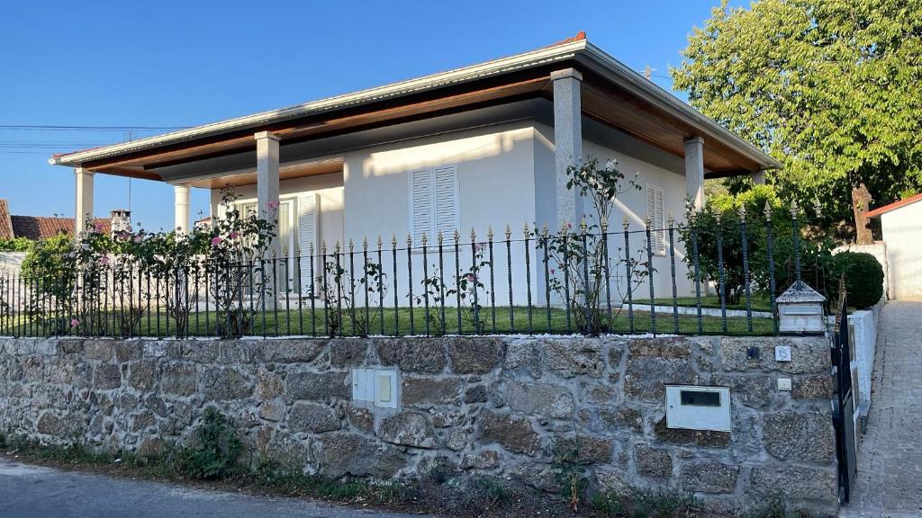 a house behind a stone wall with a fence at Ramboia Guest House in São Pedro do Sul