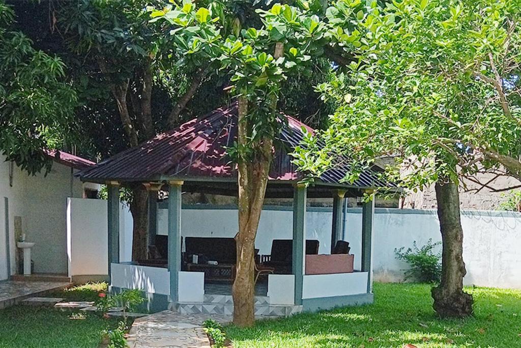 a gazebo in a yard with two trees at Royal Garden Residence in Apégame