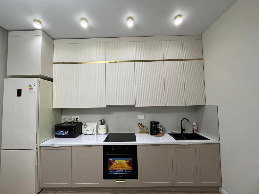 a kitchen with white cabinets and a sink and a refrigerator at ЖК Geneva in Astana