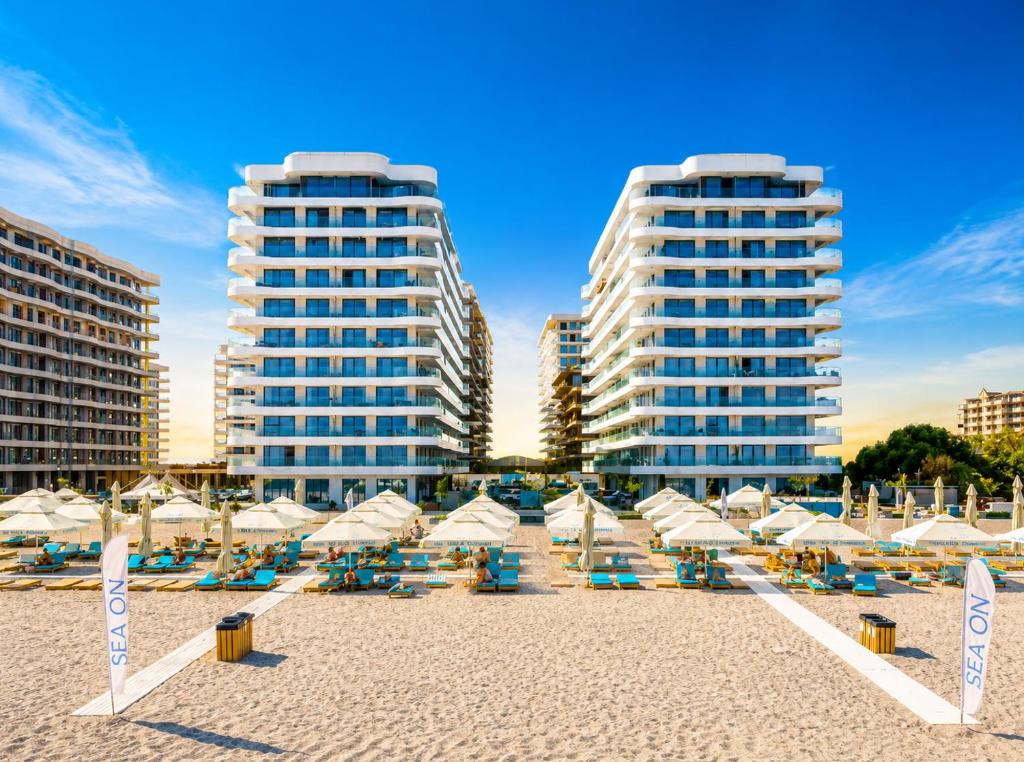 a beach with umbrellas and chairs and buildings at Studio Sea On Beach in Mamaia