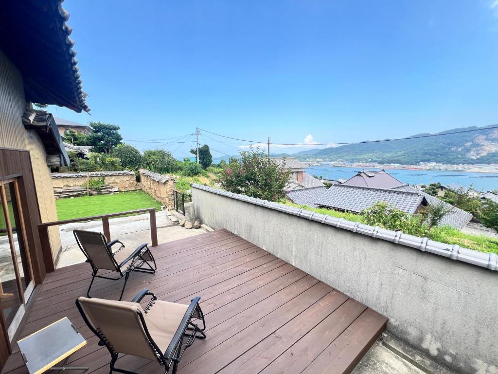 a wooden deck with two chairs and a table on it at 瀬戸内海を望む庭付き古民家サウナ宿 一棟貸切 in Takamatsu