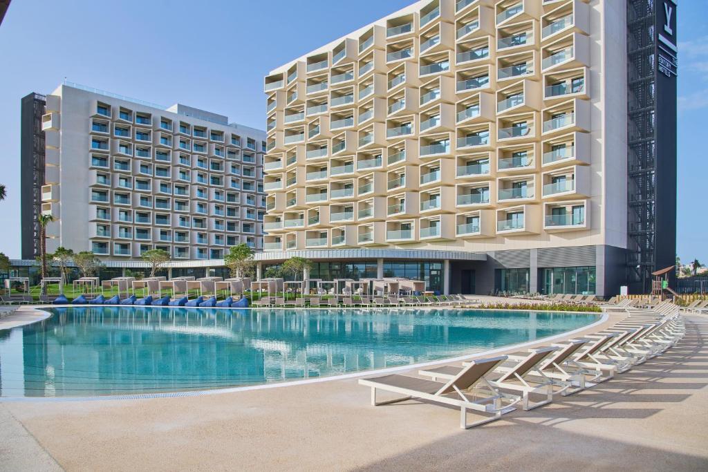 a hotel with a swimming pool with chairs and a building at The Editory by the Sea Lagos in Lagos