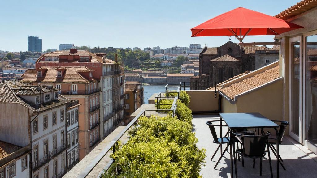 a balcony with a table and chairs and an umbrella at The Editory House Ribeira Porto Hotel in Porto
