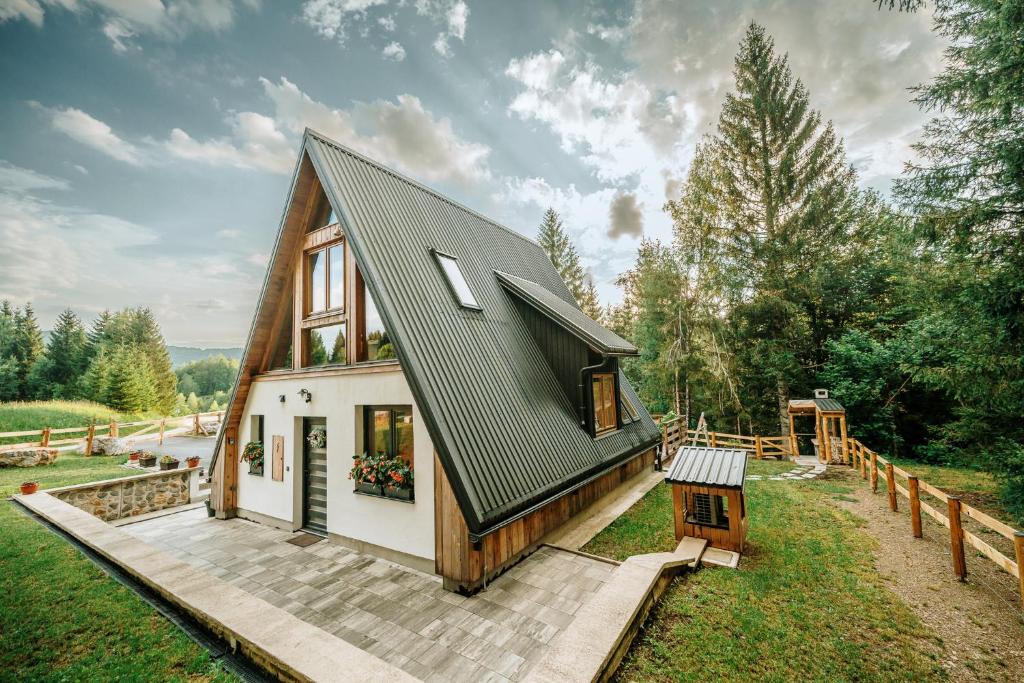 a small house with a black roof on a field at Duh šume in Kupjak