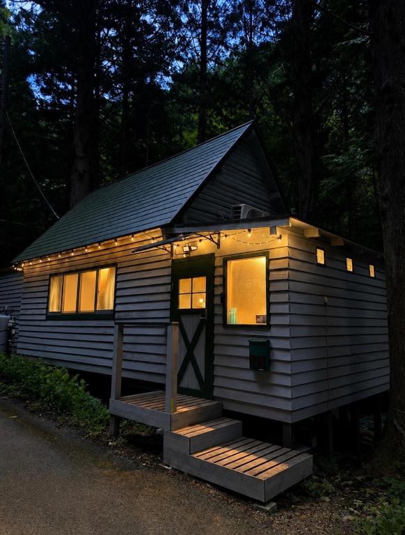 a tiny house with lights on it in the woods at Kozakura Cottage II in Hamamatsu