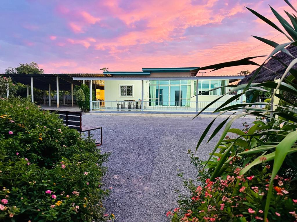 a white house with a sunset in the background at หลัง 1 เฌอเฌอ การ์เด้น เฮาส์ ที่พักคำชะโนด in Ban Nong Sawang