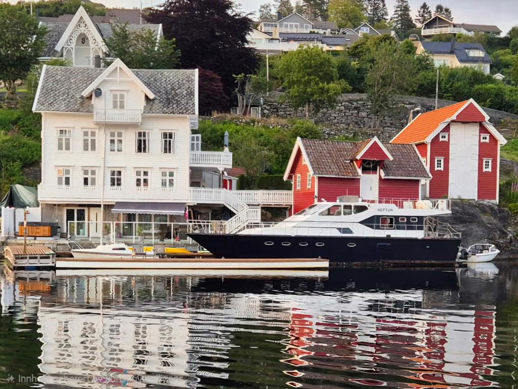 a boat docked at a marina in front of houses at Boat Included, Waterfront Villa, Near Bergen in Lindås