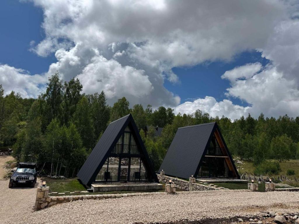 a large building with a black roof on a field at Frogland in Žabljak