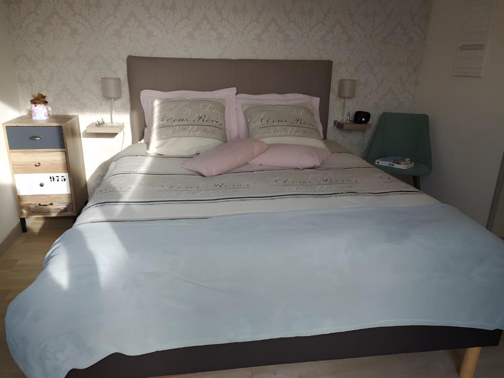 a large white bed with a pink pillow on it at Chambre Terre et Mer-Millet in Gréville-Hague