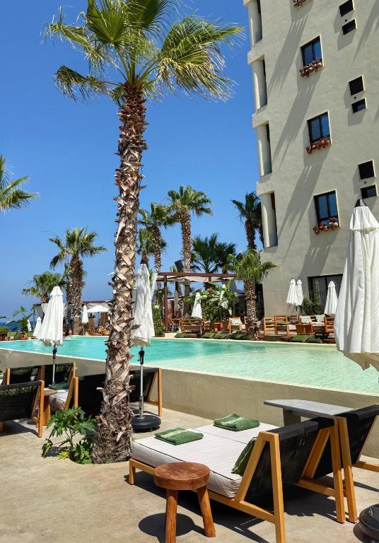 a hotel with a palm tree next to a swimming pool at Be Batroun in Batroûn