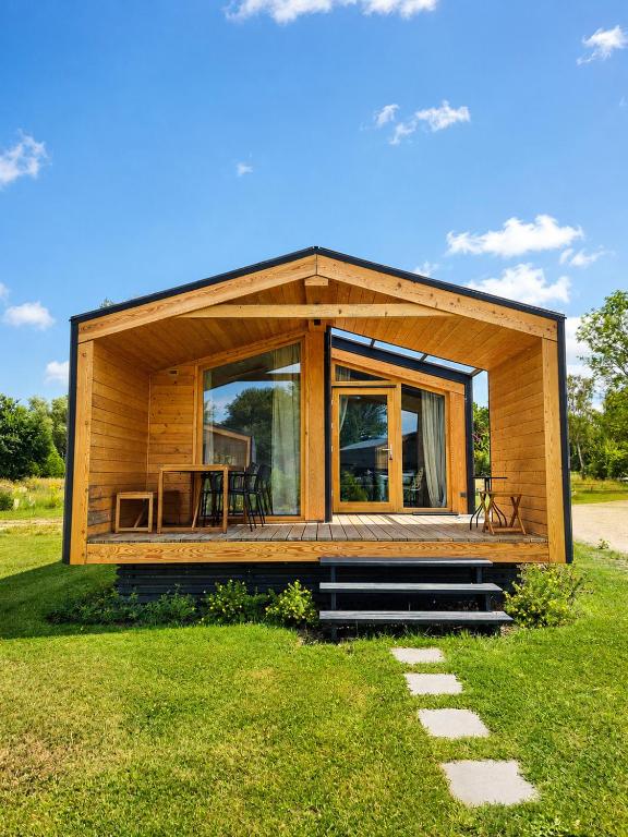 a small house with a large window on a grass field at 309 Stylisches Tiny House für Familien in Bleckede