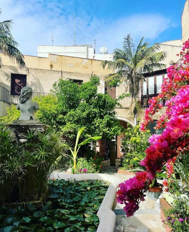 a garden with flowers and a statue in a building at Antica Corte delle Ninfee, Historical Private Villa in Trapani