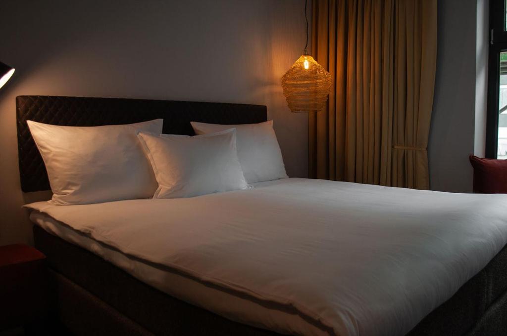 a bed with white sheets and pillows in a room at gambino hotel GOETHE26 in Munich