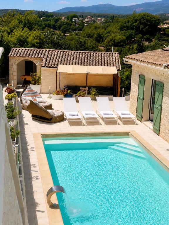 a swimming pool with lounge chairs and a house at villa plaisirs in Saint Paul de Vence