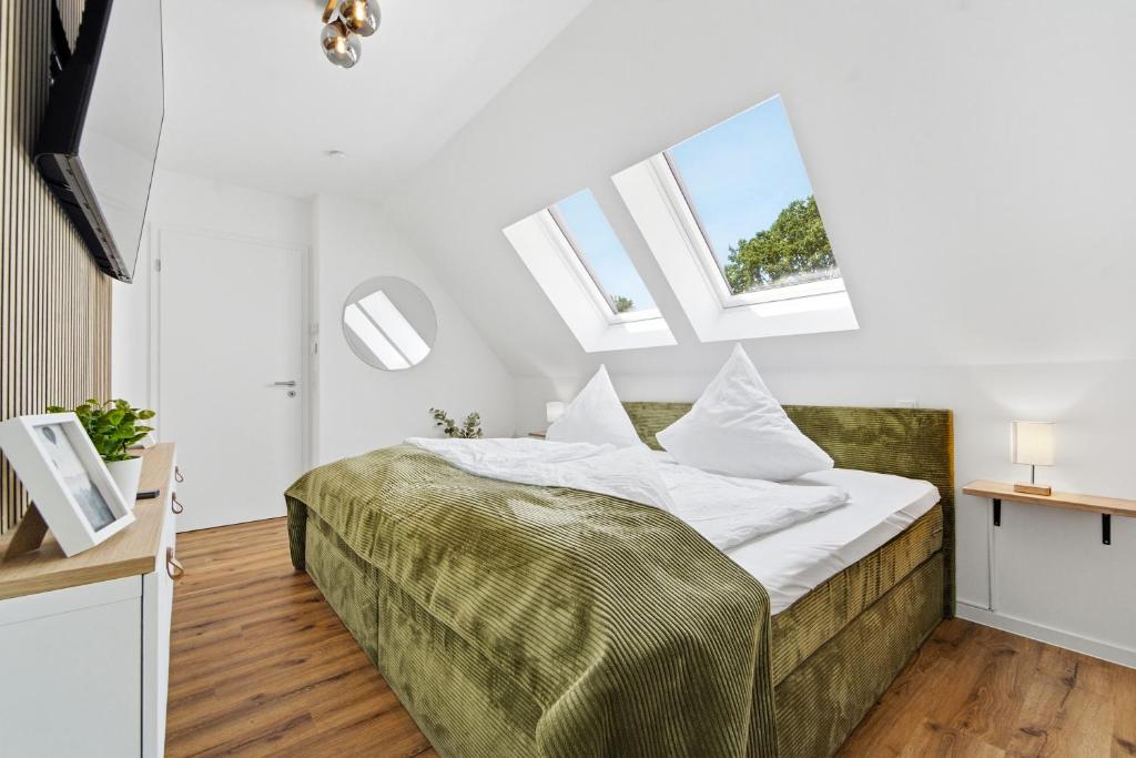 ein Schlafzimmer mit einem Bett mit weißen Laken und Fenstern in der Unterkunft Neu! Auszeit an der "Grenzfarm" - Stilvolle und geräumige FeWo - perfekt für Radfahrer und Familien in Nordhorn