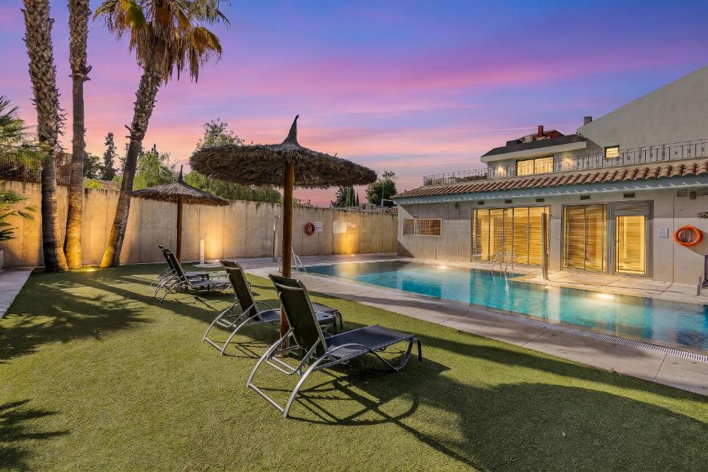 a house with a swimming pool with chairs and an umbrella at Spa Jardines de Lorca in Lorca