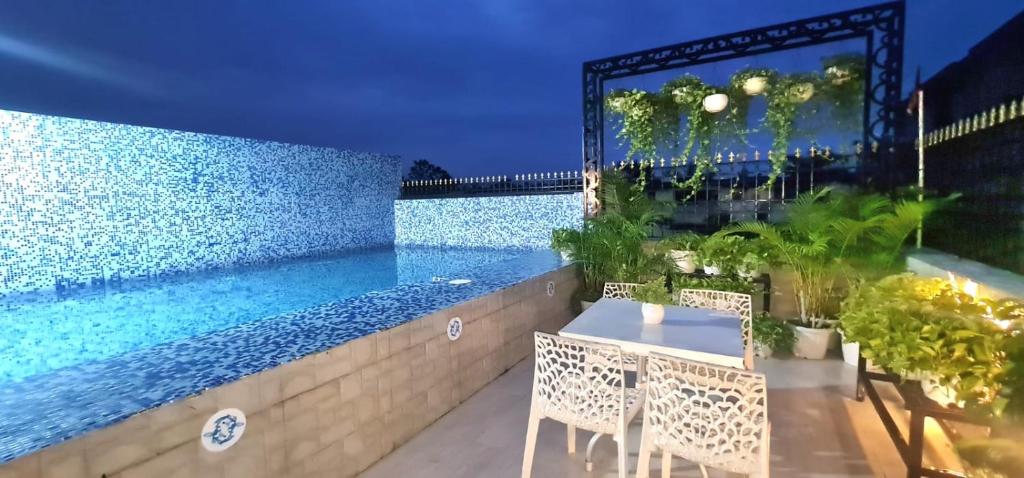 a patio with a table and chairs next to a swimming pool at Vedic village Rai villa in Sikarpur