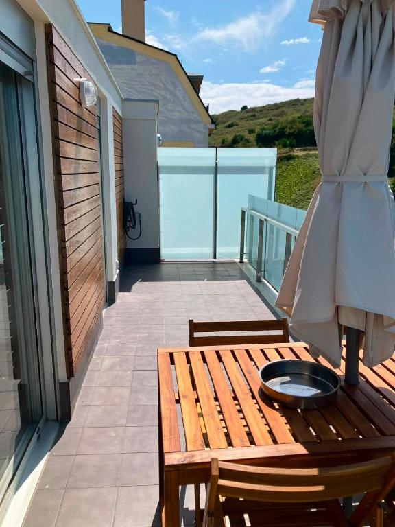 a wooden table on a balcony with an umbrella at Apartamentos en playa Canido in Malpica