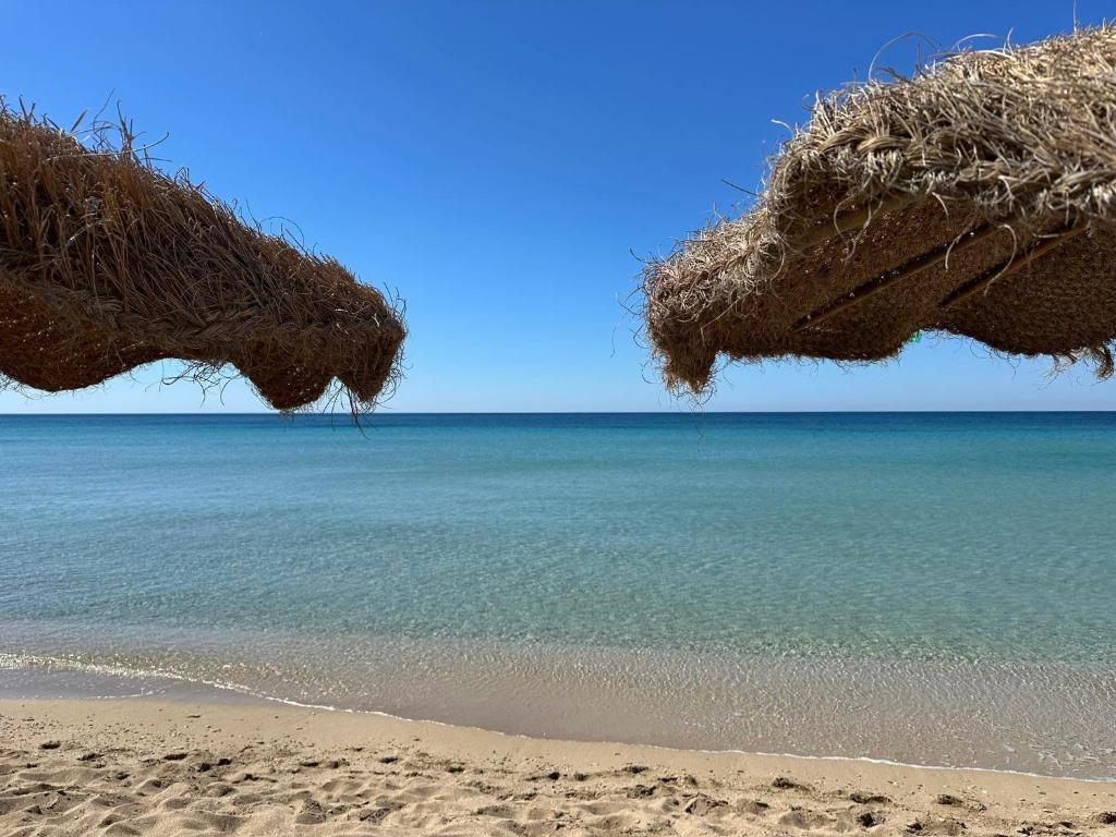 Blick aufs Meer von einem Strand mit zwei Strohschirmen in der Unterkunft Tuareg Hotel in Campomarino