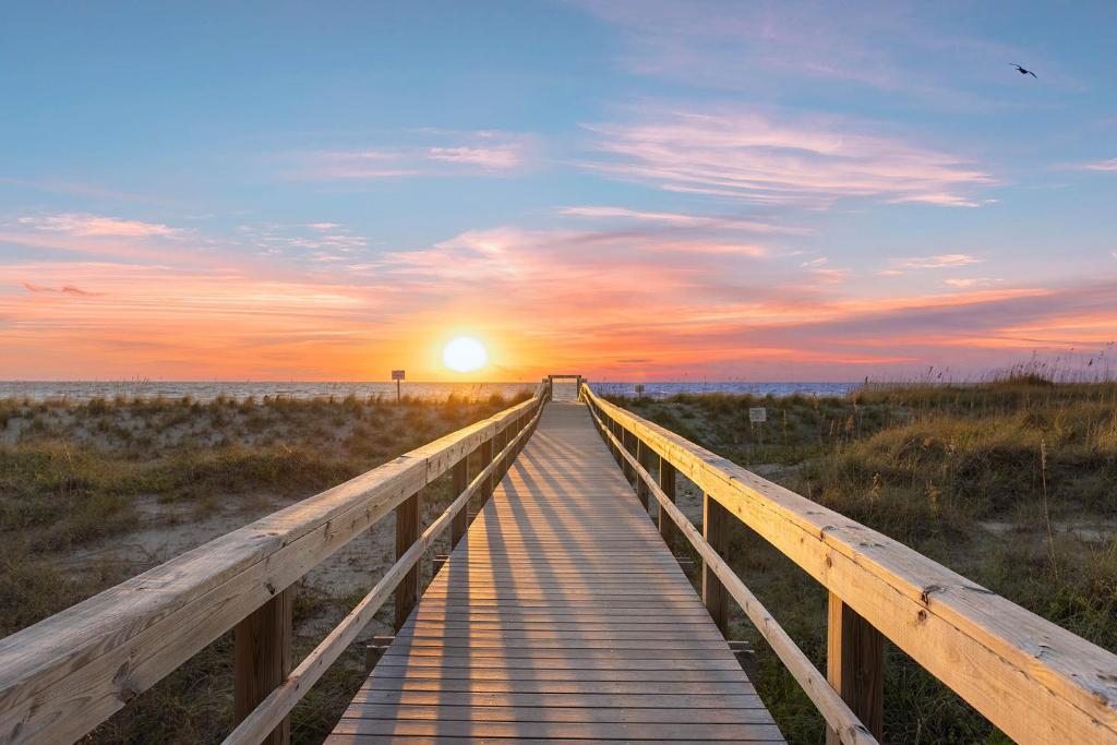 a wooden boardwalk leading to the beach at sunset at The Gardens 703 in Tybee Island