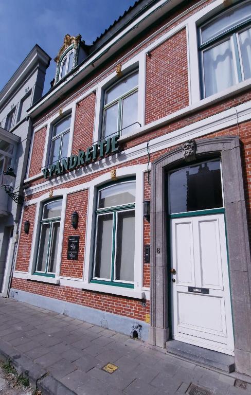 a brick building with a white door on a street at Suite Stays Bruges - Pandreitje 6 in Bruges